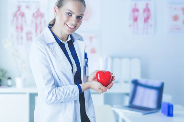 Lékař se stetoskopem vyšetřuje červené srdce, izolované na bílém pozadí — Stock fotografie