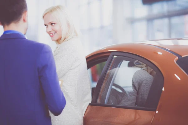 Concessionnaire avec femme se tient près d'une nouvelle voiture dans le showroom — Photo