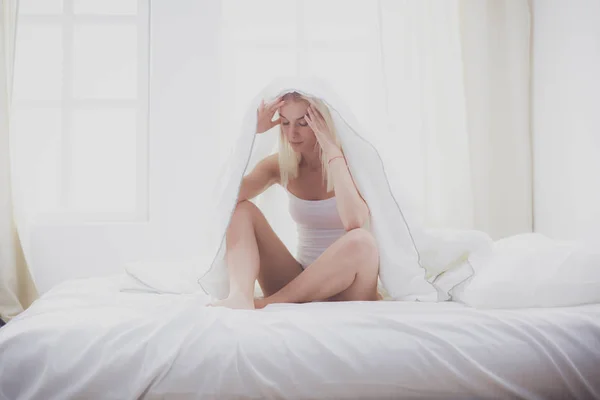 Улыбающаяся женщина под одеялом в своей спальне — стоковое фото