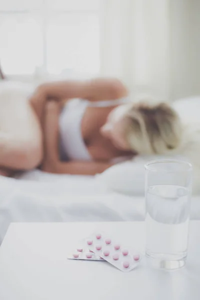 Joven hermosa mujer con pastillas tumbado en la cama en el dormitorio — Foto de Stock