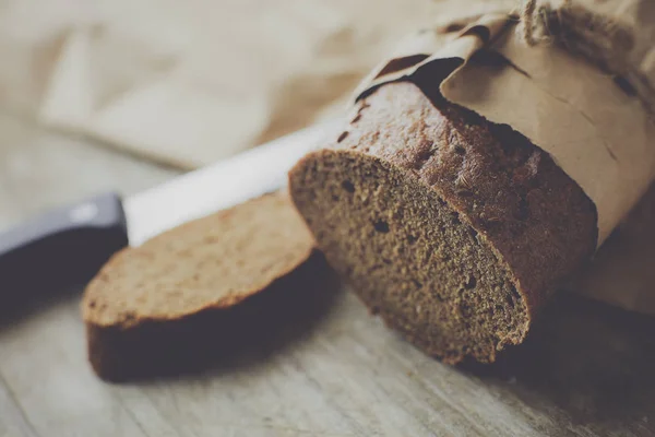 Una pagnotta di pane confezionata in carta su un tavolo di legno. — Foto Stock