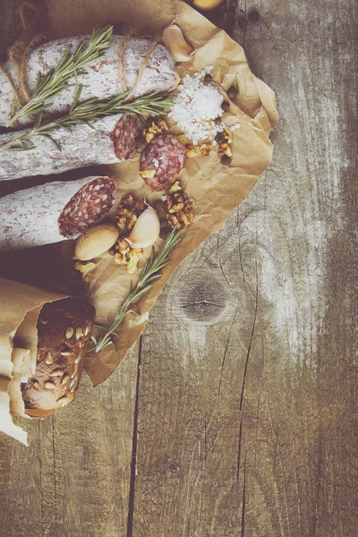 意大利腊肠海盐，迷迭香，大蒜和坚果在纸上。乡村风格。顶部视图. — 图库照片