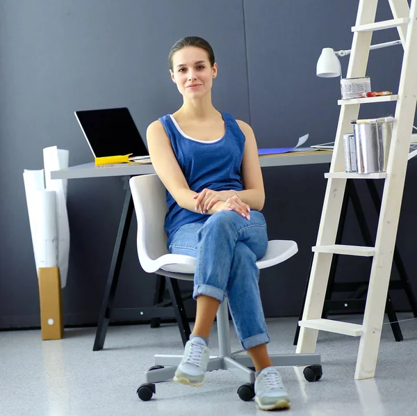 Mladá žena sedí na stole v kanceláři — Stock fotografie