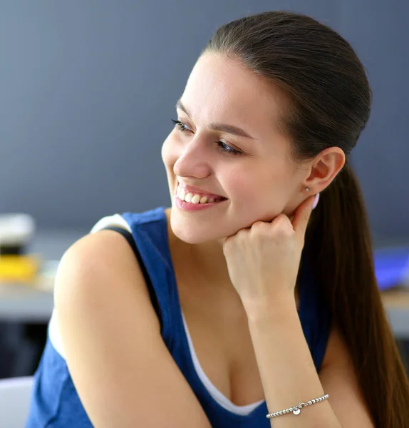 Young woman sitting on the desk in office — Stock Photo, Image