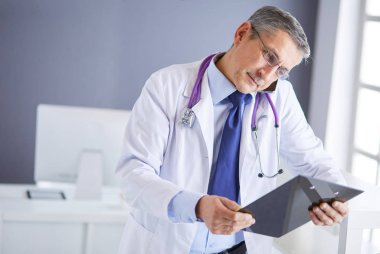 Erkek doktor hastanedeki panoya notlar yazıyor.