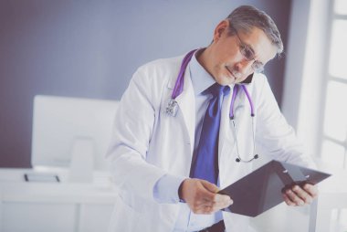 Erkek doktor hastanedeki panoya notlar yazıyor.