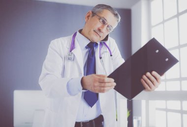 Erkek doktor hastanedeki panoya notlar yazıyor.