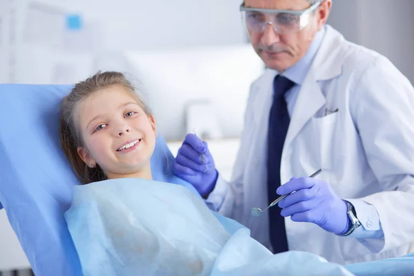 Девочка, сидящая в кабинете дантиста — стоковое фото