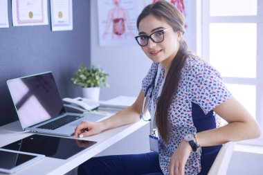 Parlak bir ofiste konuşan iki doktor.