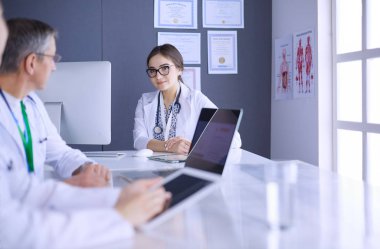 Ciddi bir tıbbi ekip parlak bir ofiste dizüstü bilgisayar kullanıyor.