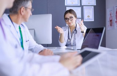 Ciddi bir tıbbi ekip parlak bir ofiste dizüstü bilgisayar kullanıyor.