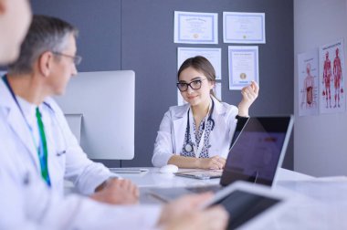 Ciddi bir tıbbi ekip parlak bir ofiste dizüstü bilgisayar kullanıyor.