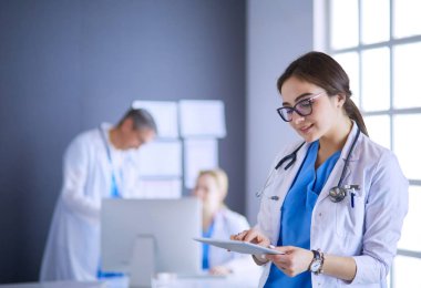 Hastane lobisinde tablet bilgisayar kullanan kadın doktor.