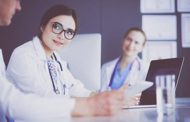 Ciddi bir tıbbi ekip parlak bir ofiste dizüstü bilgisayar kullanıyor.