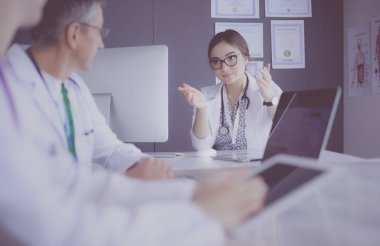 Ciddi bir tıbbi ekip parlak bir ofiste dizüstü bilgisayar kullanıyor.