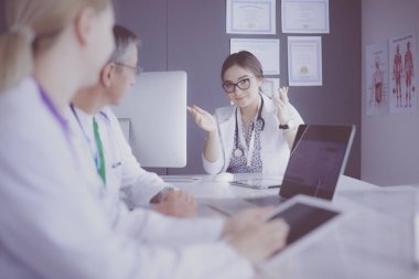 Ciddi bir tıbbi ekip parlak bir ofiste dizüstü bilgisayar kullanıyor.