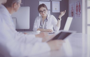 Ciddi bir tıbbi ekip parlak bir ofiste dizüstü bilgisayar kullanıyor.