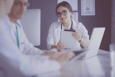 Ciddi bir tıbbi ekip parlak bir ofiste dizüstü bilgisayar kullanıyor.