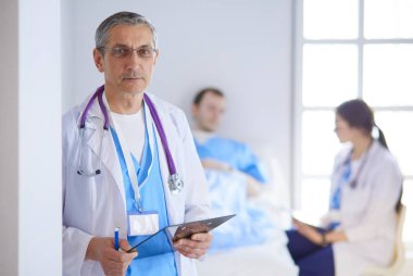 Doktor bir hastanın ve doktorun önünde klasörü tutuyor.