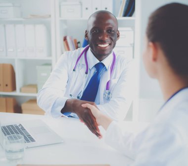 Ofiste tokalaşırken gülümseyen iki genç doktor.