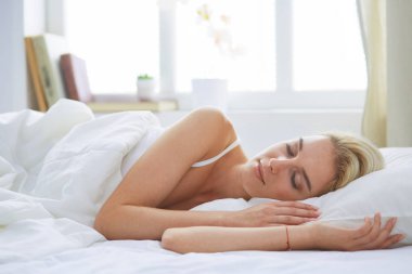 Güzel bir kadın yatağında uzanıyor.