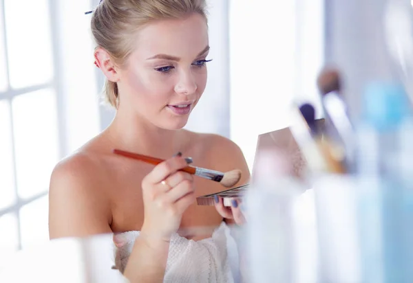 A picture of a young woman applying face powder in the bathroom — Stock Photo, Image
