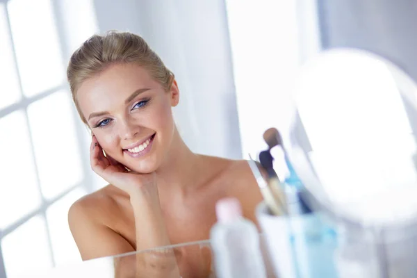 Giovane donna in accappatoio guardando nello specchio del bagno — Foto Stock