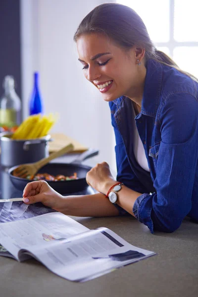 Ung kvinna äter frukost och läsa tidningen — Stockfoto