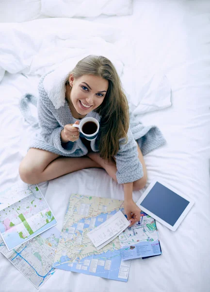 Giovane donna rilassata seduta sul letto con una tazza di caffè e tablet digitale — Foto Stock