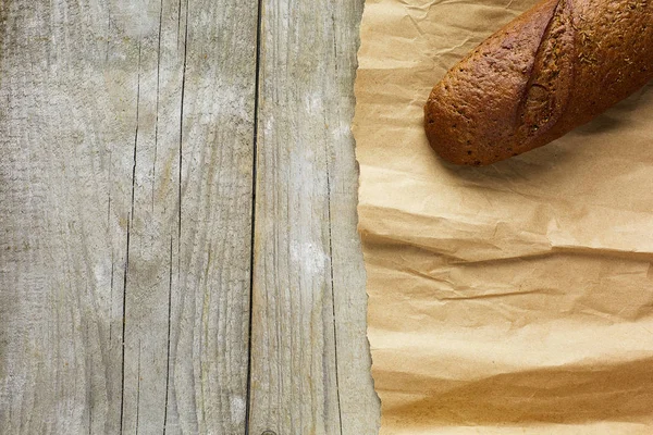 A loaf of Bread packed in paper on wooden table.