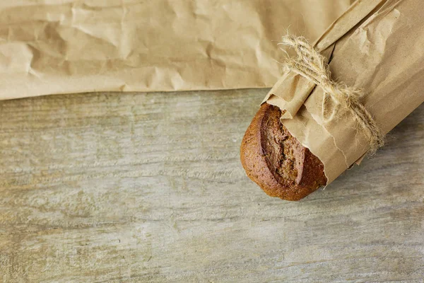 Brood in plakjes, verpakt in papier op houten tafel. — Stockfoto