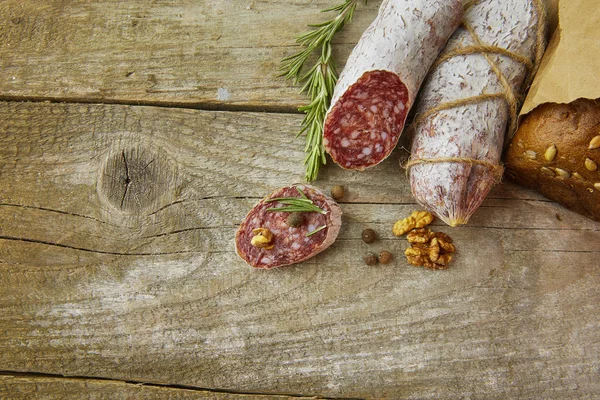 Italienische Salami mit Meersalz, Rosmarin, Knoblauch und Nüssen auf Papier. Rustikaler Stil. Nahaufnahme. — Stockfoto