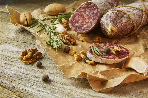 Italienische Salami mit Meersalz, Rosmarin, Knoblauch und Nüssen auf Papier. Rustikaler Stil. Nahaufnahme. — Stockfoto