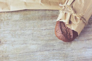 Dilimlenmiş ekmek somunu tahtadan masanın üzerinde kağıda sarılmış..