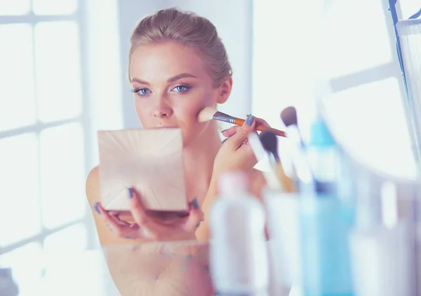 Una foto di una giovane donna che applica polvere per il viso in bagno — Foto Stock