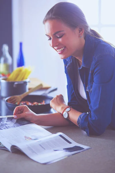 Ung kvinna äter frukost och läsa tidningen — Stockfoto