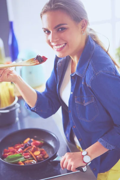 Young woman cooking healthy food holding a pan with vegetables is it. Healthy lifestyle, cooking at home concept