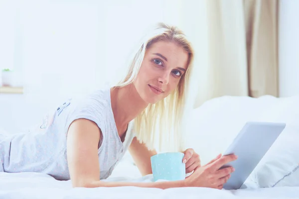 Chica sosteniendo tableta digital con pantalla en blanco y sonriendo a la cámara en el dormitorio — Foto de Stock