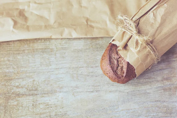 Skivad brödlimpa förpackad i papper på träbord. — Stockfoto