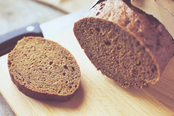 Een brood verpakt in papier op houten tafel. — Stockfoto