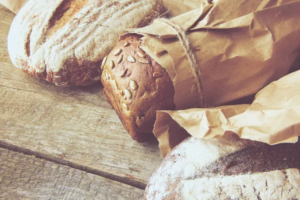 A loaf of Bread packed in paper on wooden table.