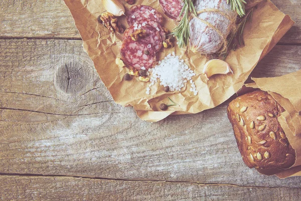 意大利腊肠, 含海盐, 迷迭香, 大蒜和坚果在纸上。质朴的风格。特写. — 图库照片