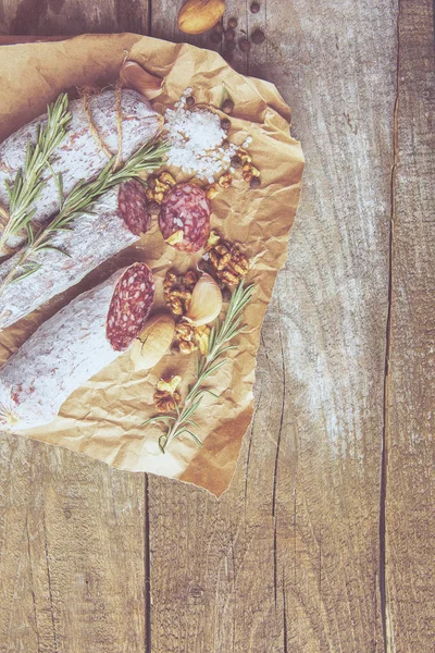 意大利腊肠, 含海盐, 迷迭香, 大蒜和坚果在纸上。质朴的风格。特写. — 图库照片
