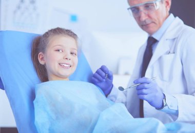 Küçük kız dişçi ofisinde oturuyor.