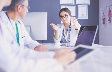 Ciddi bir tıbbi ekip parlak bir ofiste dizüstü bilgisayar kullanıyor.