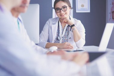 Ciddi bir tıbbi ekip parlak bir ofiste dizüstü bilgisayar kullanıyor.