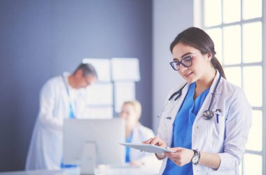 Hastane lobisinde tablet bilgisayar kullanan kadın doktor.