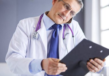 Erkek doktor hastanedeki panoya notlar yazıyor.