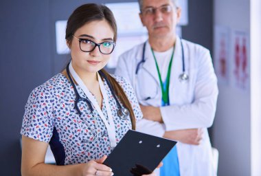 Bir doktor ekibi, kadın ve erkek, ofiste bekliyorlar.