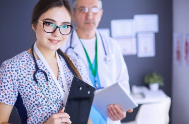 Bir doktor ekibi, kadın ve erkek, ofiste bekliyorlar.